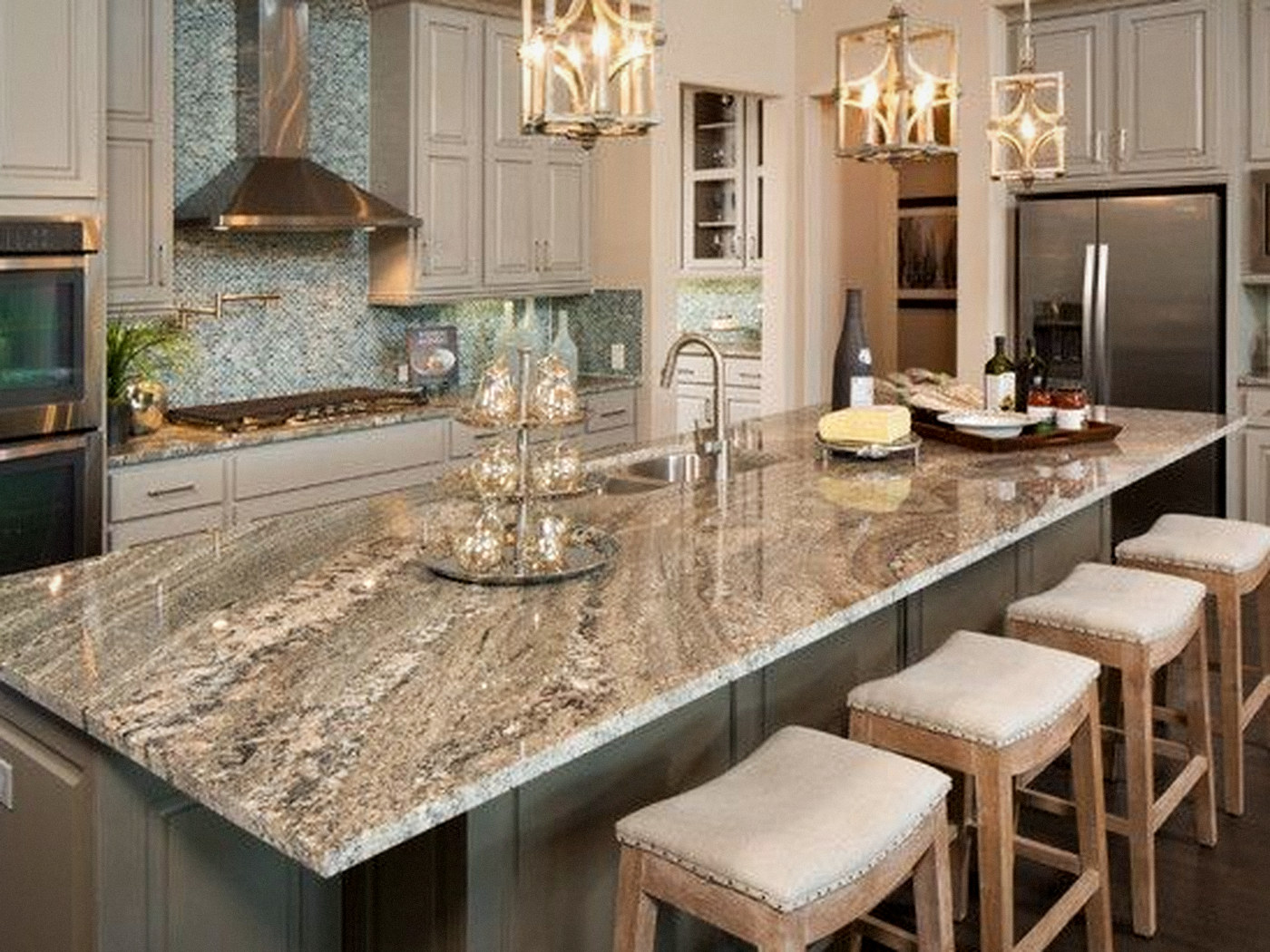 Open kitchen with a long granite island, linen bar stools, pendant lanterns and a mosaic tile backsplash in Denver, CO