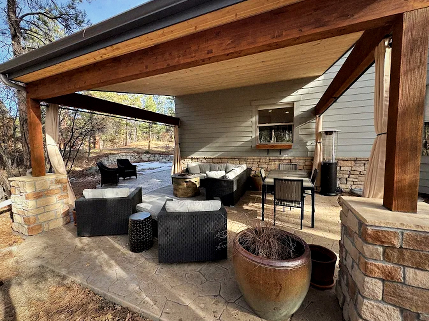 Timber-framed covered patio with stone columns, stamped concrete and lounge seating in Castle Rock, CO